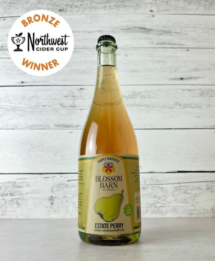 Photo of a Bottle of Blossom Barn Estate Perry with a 'Bronze Northwest Cider Cup Winner' label on a white wooden background