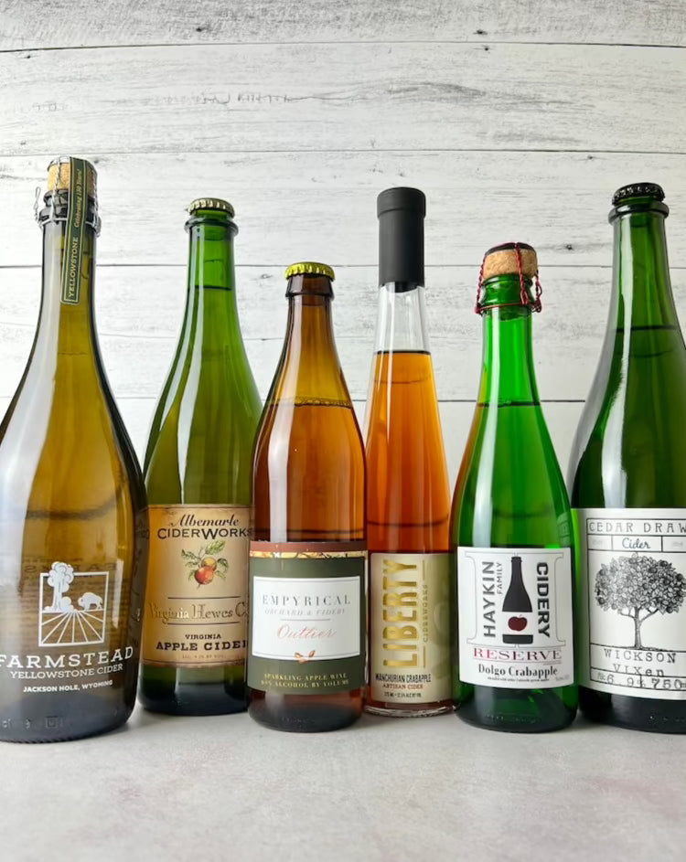 6 bottles of crabapple cider, from left to right: Farmstead Yellowstone, Albemarle Virginia Hewe's Crab, Empyrical Outlier, Liberty Manchurian, Haykin Dolgo Crabapple, and Cedar Draw Wickson Vixen