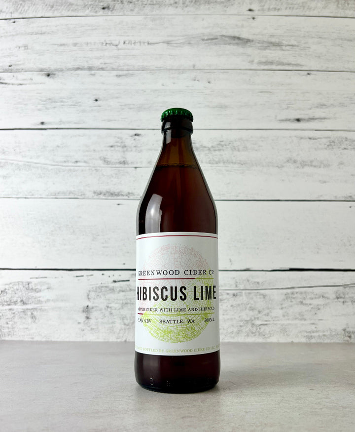 Photo of a 500 mL Bottle of Greenwood Cider Co. Hibiscus Lime cider on a wooden surface