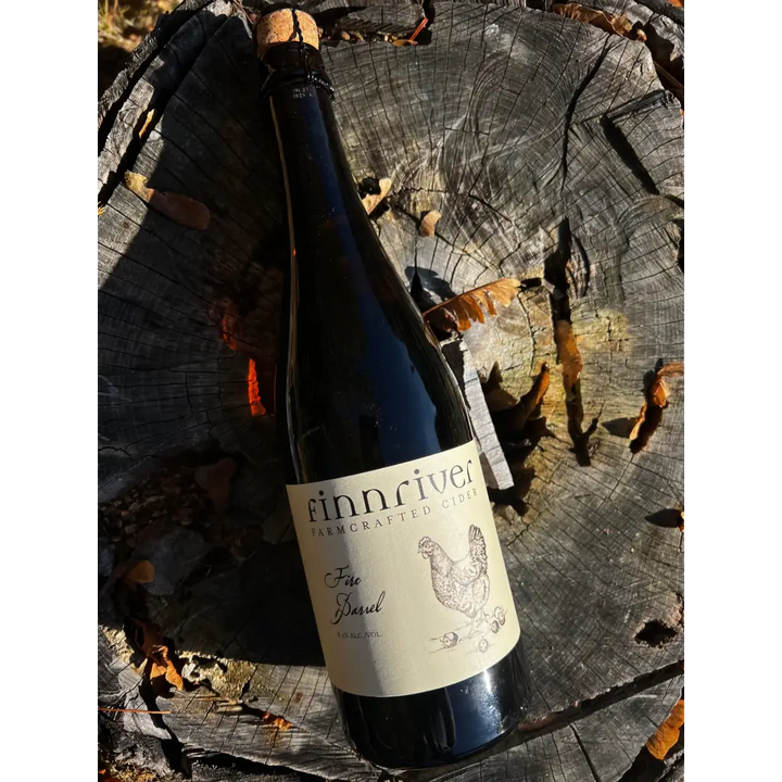 Bottle of Finnriver Fire Barrel cider laying on a stump