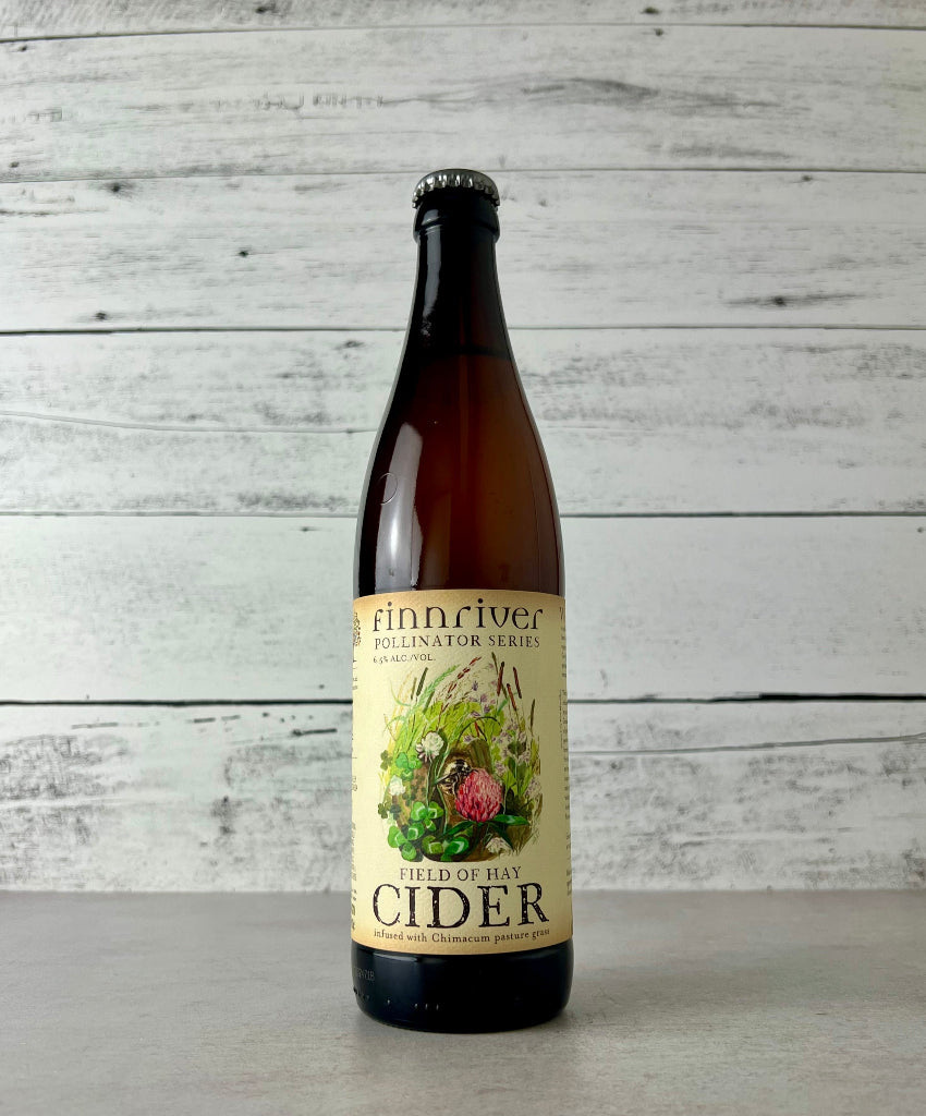 Photo of a 500 mL Bottle of Finnriver Field of Hay Cider on a white wooden background