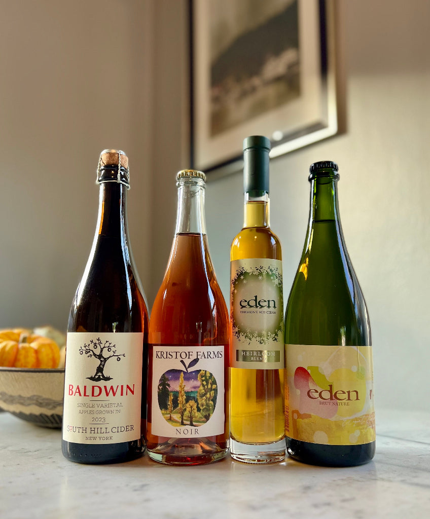 Photo of 4-bottles of cider, from left to right: South Hill Cider Baldwin, Kristof Farms Noir, Eden Heirloom Ice Cider, Eden Brut Nature