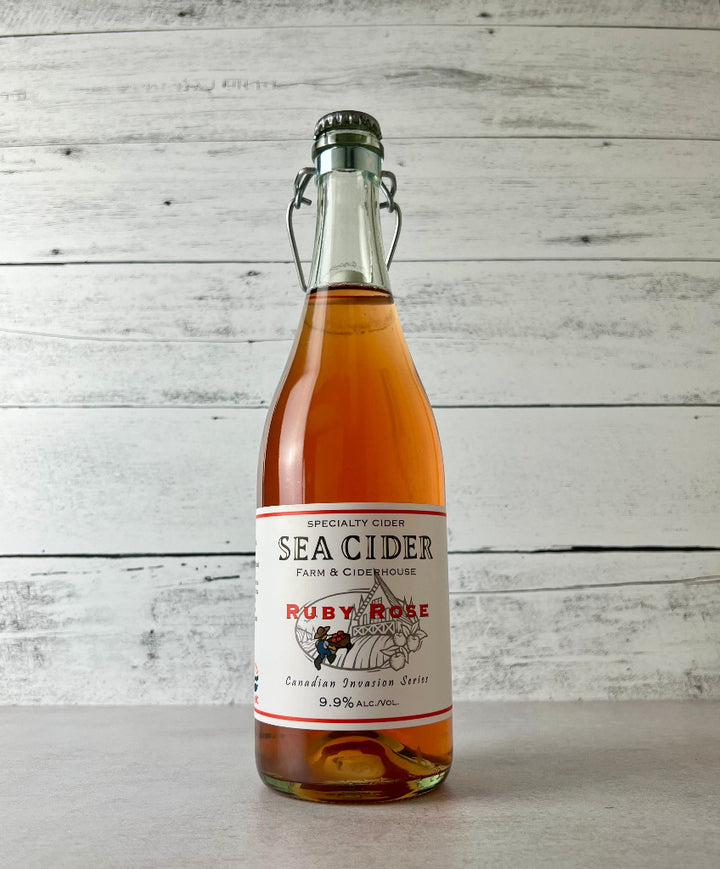 Photo of a 750 mL clear glass bottle of bright pink colored Sea Cider Ruby Rose Canadian Invasion Series cider
