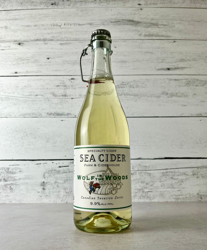 Photo of a 750 mL clear glass bottle of Sea Cider Wolf in the Woods Canadian Invasion Series cider with flip top