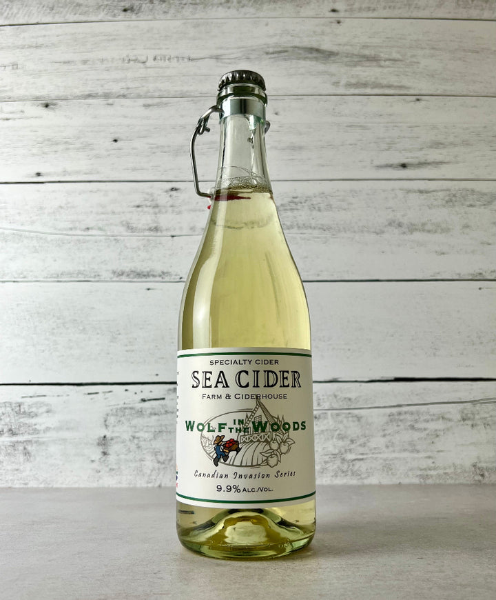 Photo of a 750 mL clear glass bottle of Sea Cider Wolf in the Woods Canadian Invasion Series cider with flip top
