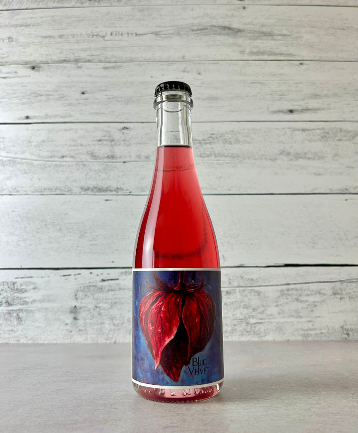 Photo of a 375 mL bottle of Botanist & Barrel Blue Velvet Cider. Bright pink cider in a clear bottle.
