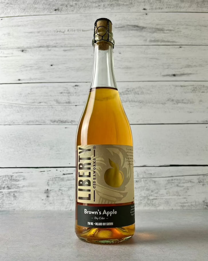 750 mL clear glass bottle of Liberty Ciderworks Brown's Apple Dry Cider with cork and cage top