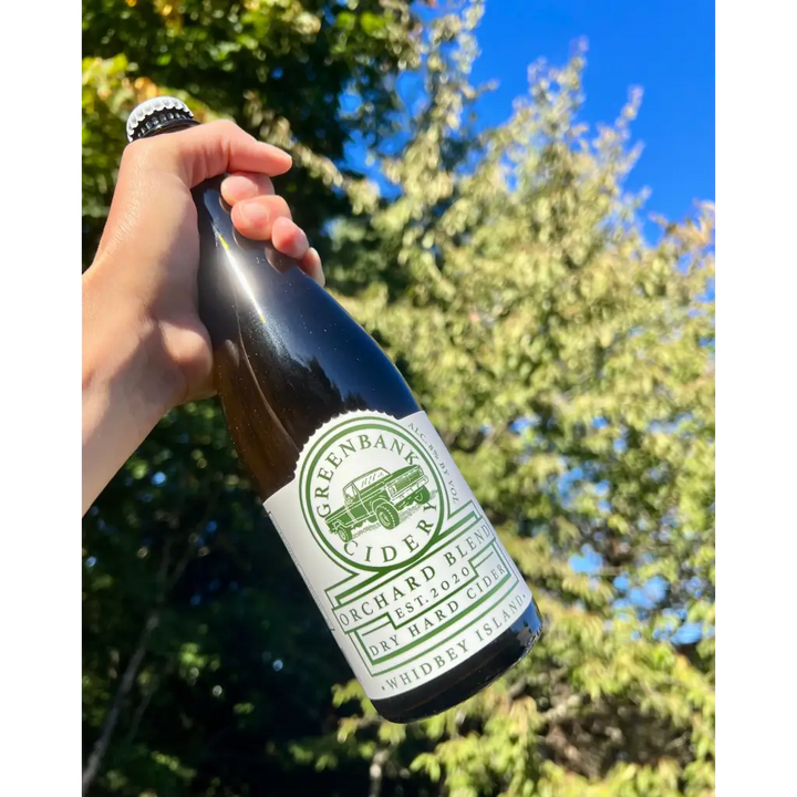 500 mL bottle of Greenbank Cidery Orchard Blend Dry Hard Cider - Whidbey Island - with blue sky and tree in background
