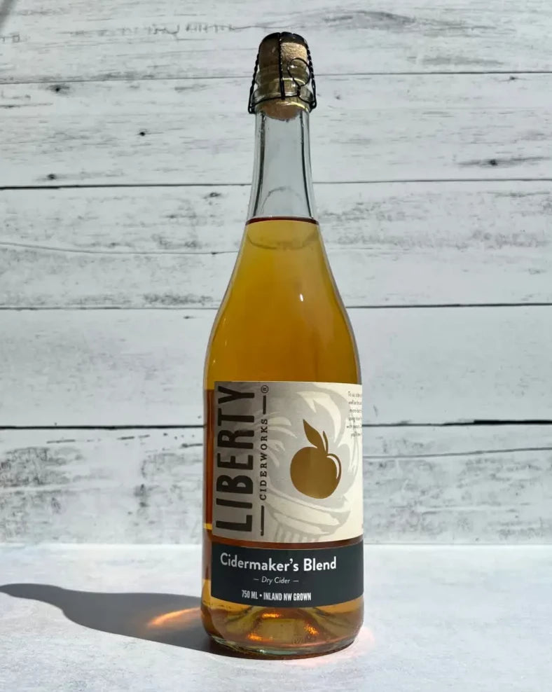 750 mL clear glass bottle of Liberty Ciderworks Cidermaker's Blend Dry Cider with cork and cage top