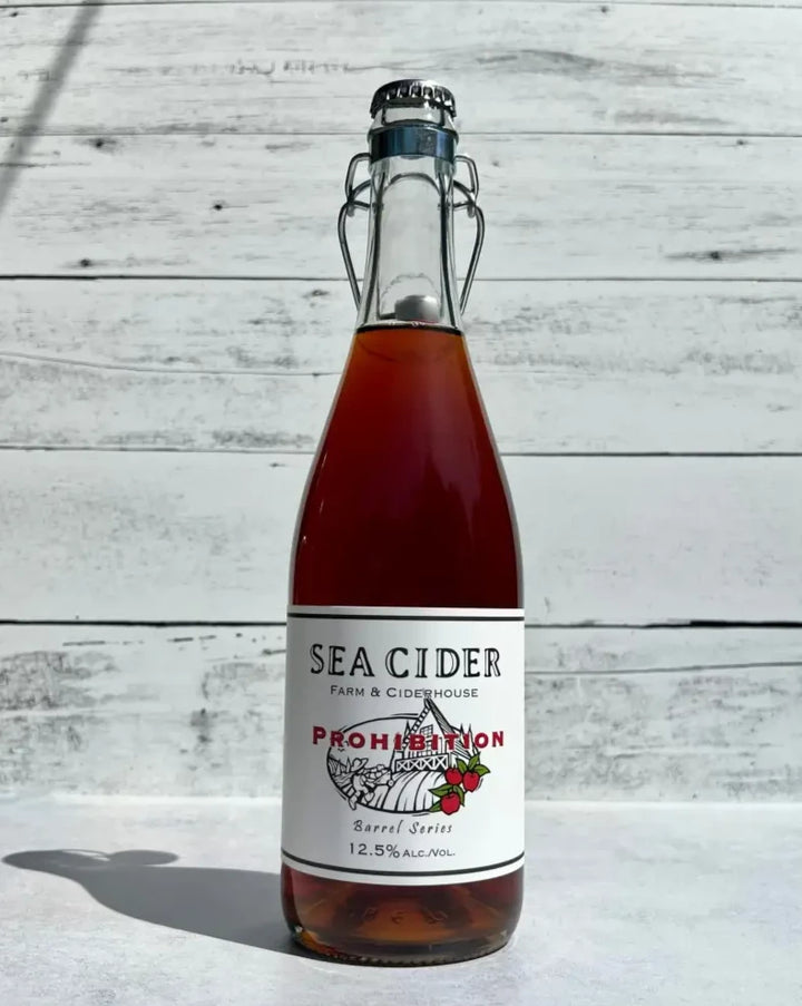750 mL clear glass bottle of copper colored Sea Cider Farm & Ciderhouse Prohibition Barrel Series cider with flip top